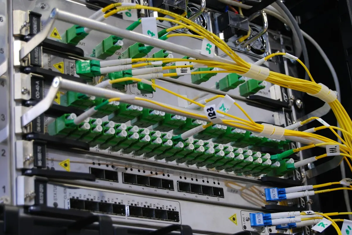 Yellow fiber optic cables connected to a network switch in a rack