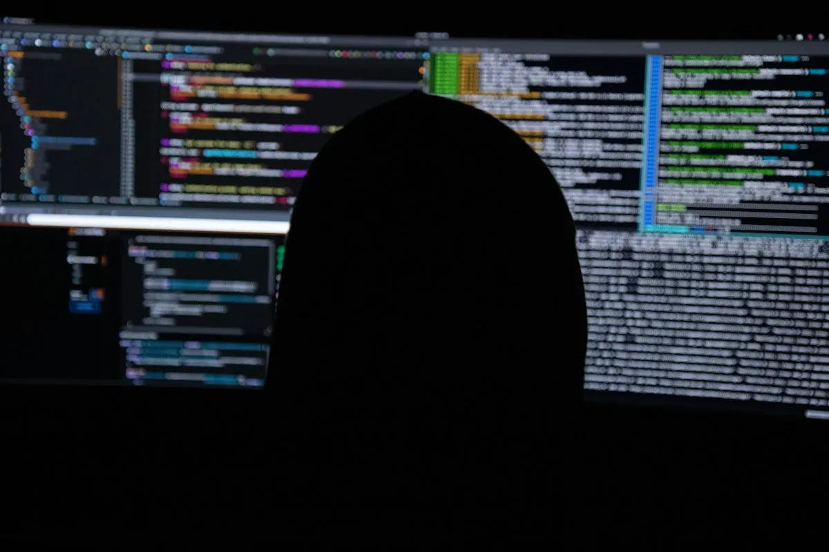 Silhouette of a person in front of screens full of computer code