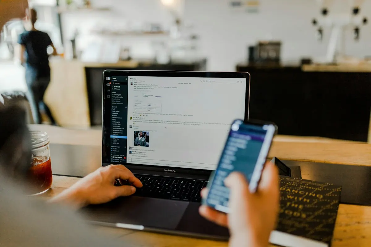 Person working on a laptop and a smartphone at a cafe table