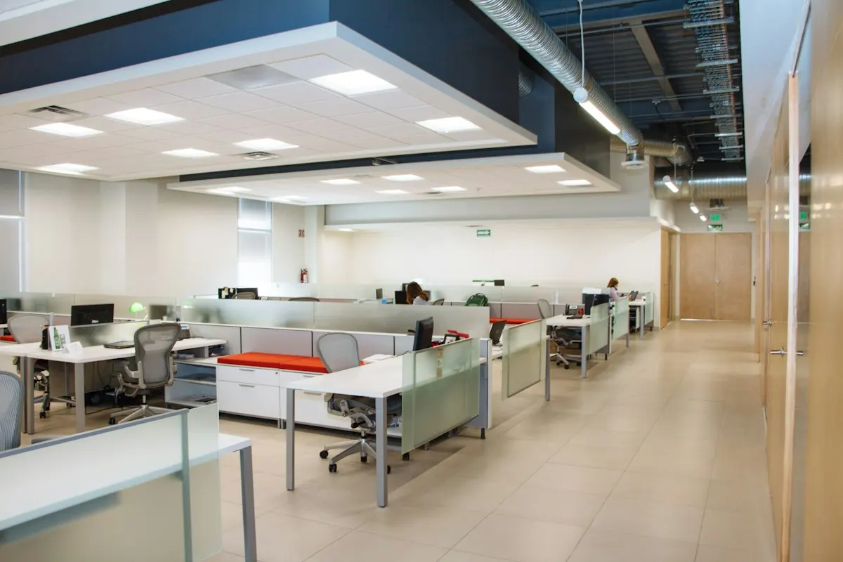 Empty open-plan office with white desks and glass partitions